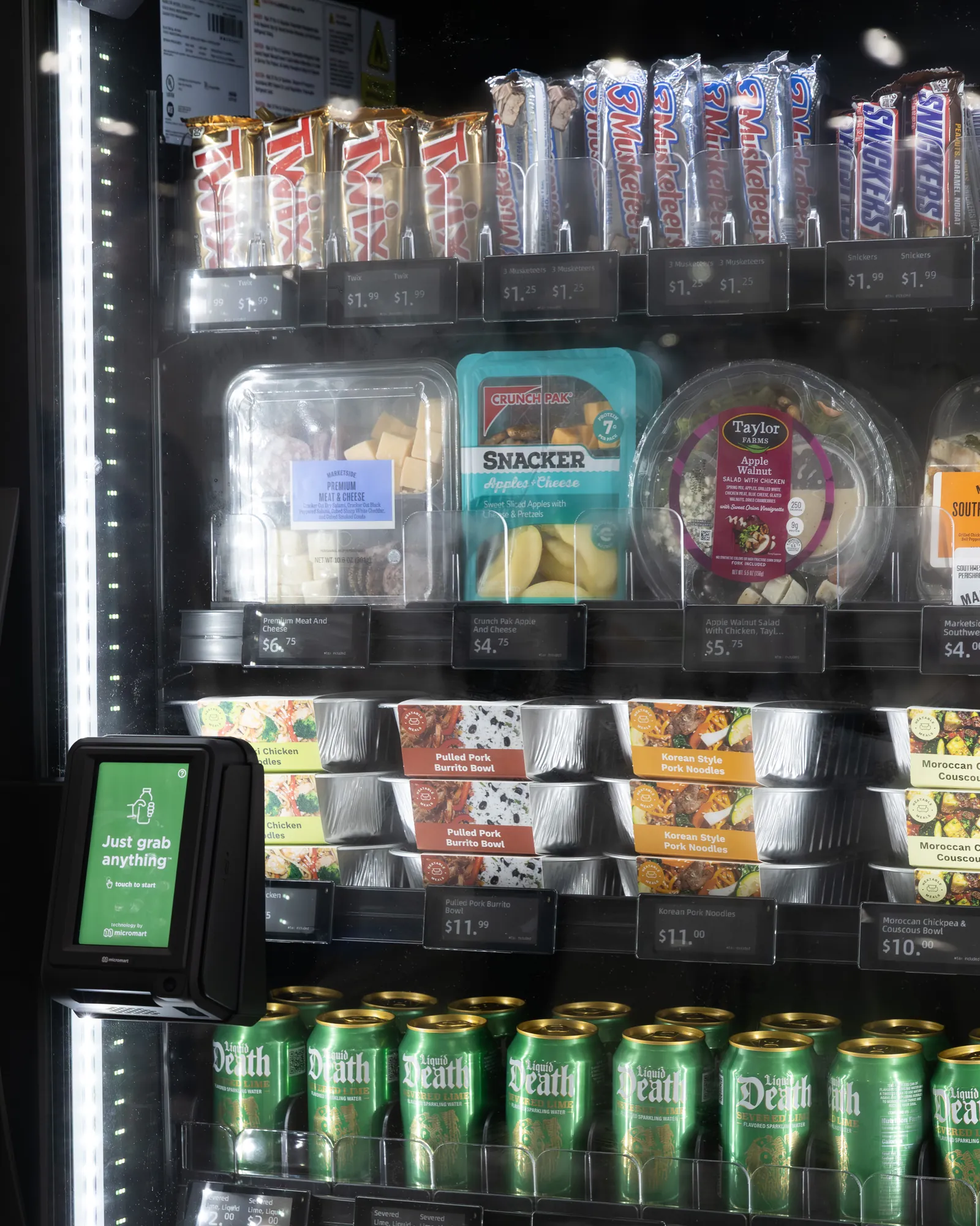 Inside a stocked smart cooler: sandwiches, salads, burrito bowls and cold drinks, each shelf edge showing its price.